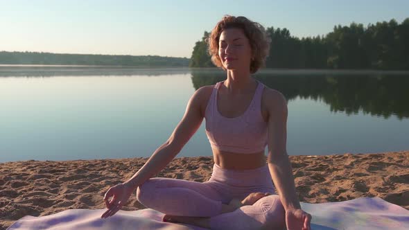 Woman is meditating in the lotus position, doing yoga on a sandy beach