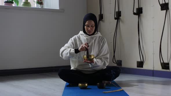 A Young Woman in Hijab Does Meditation Ritual with Driving the Pusher Along the Edges of the Tank on