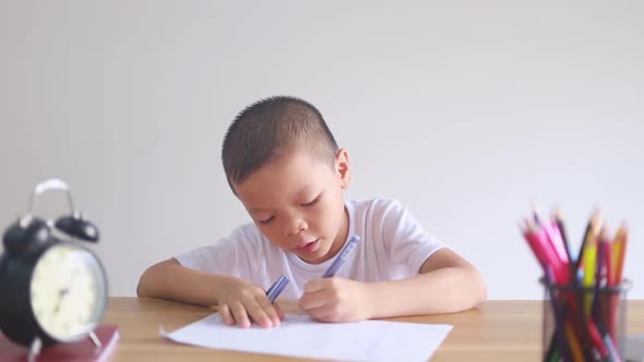 boy sitting and doing homework, drawing, coloring