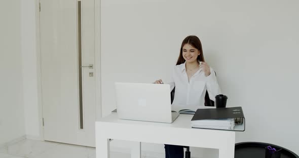 Happy Office Girl Smiling When Sitting at Table and Looking on Laptop