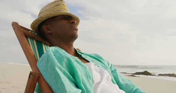 Side view of African american man sleeping in a sun lounger on the beach 4k