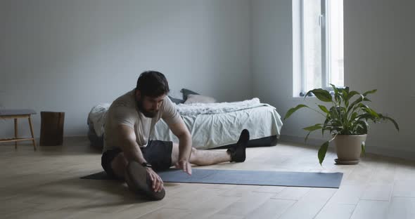 Young Man Making Stretching Legs Exercise at Home