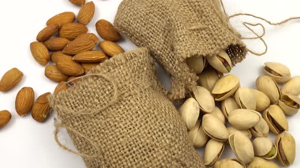 Almond and pistachio nuts in bags on white surface