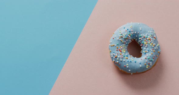 Video of donut with icing on blue and pink background