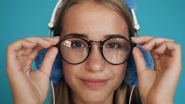 Beautiful Teen Girl in Glasses and with Headphones Looking Straight in the Camera