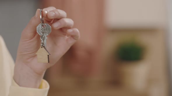 Close Up of Female Hands Holding Key with House Keychain in Hand on the Blurred Background