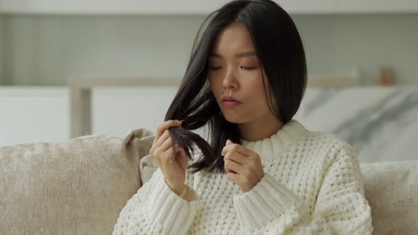 Asian Woman Sitting on the Couch with Hair Problems  Brittle Damaged Dry Dirty and Falling Out Hair