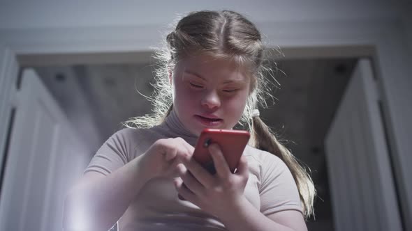 A Girl with Down Syndrome is Holding a Smartphone