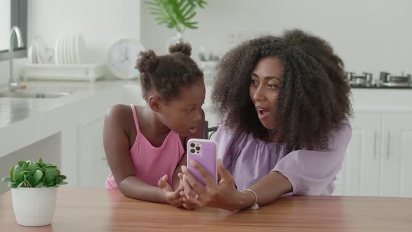 Multiethnic Young Woman with Her Charming Little Daughter Looking at the Camera While Using the