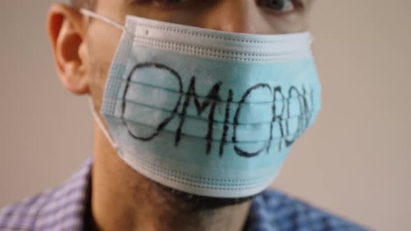 man in the gray background is spinning his head, showing a medical mask over his face