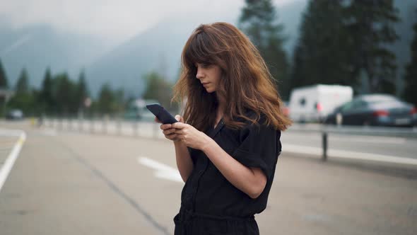 Gimbal Shot of Woman with the Phone on Background of Highway Road