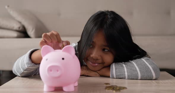 Girl putting coins into piggy bank
