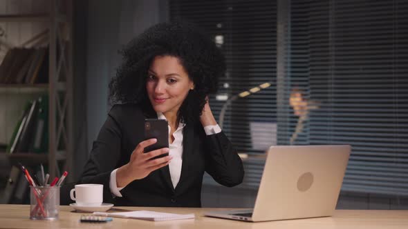 Portrait of African American Woman Typing on Laptop Then Talking on Video Call Using Smartphone