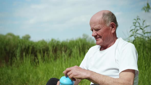 Elderly Handsome Man Enjoys Life and Drinks Pure Healthy Water From Sports Bottle After Playing