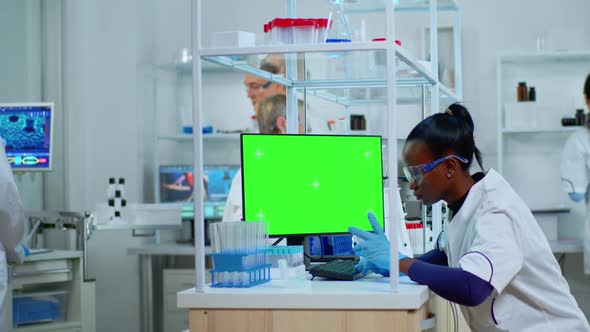 African Scientist Woman Typing on Computer with Green Mockup