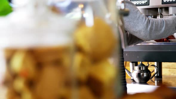 Mid section of waiter making cup of coffee