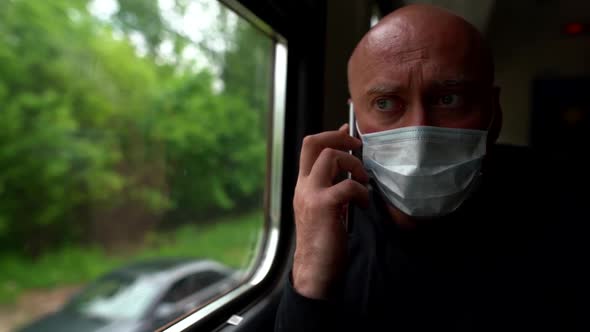 Close-up Portrait of a Bald Middle-aged Man with a Medical Mask on His Face. He Is on the Train and