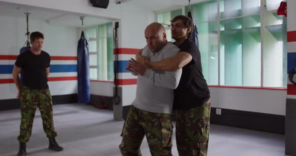 Caucasian man learning self defense from trainer in gym