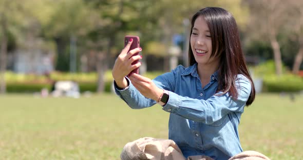 Woman use of smart phone and sitting on green lawn