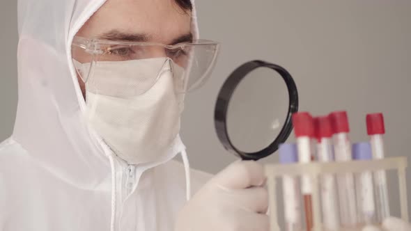 Male Scientist Is Examining Blood Tests with a Magnifying Glass