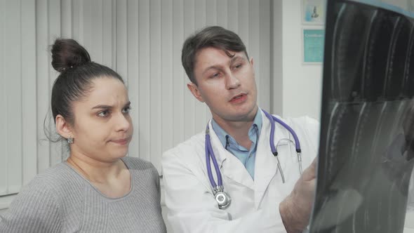 Experienced Doctor Showing Xray Scan to Female Patient