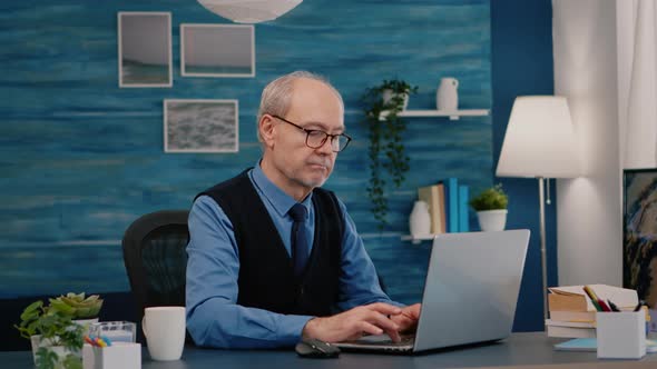 Old Freelancer Typing on Laptop Sitting in Living Room Working Remote