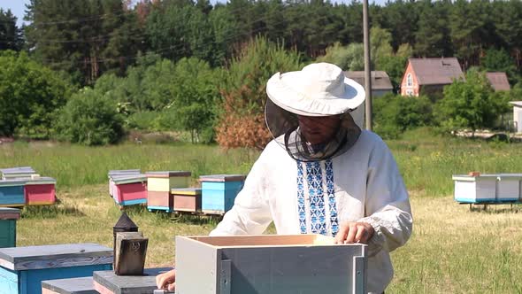 The beekeeper looks after bees, honeycombs, a lot of honey, in a protective beekeepers beast.