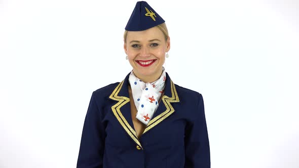 A Young Beautiful Stewardess Puts on a Cap and Smiles at the Camera - White Screen Studio