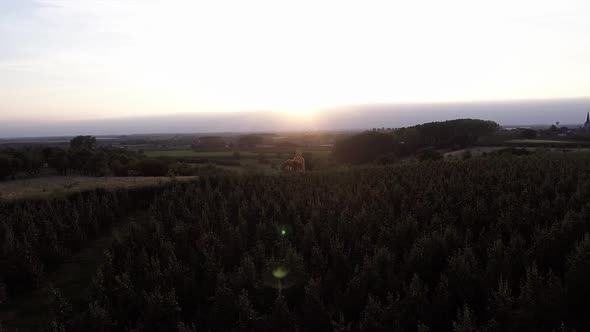 A drone shot flying to the side, seeing a see through church with the sunsetting behind it, keeping