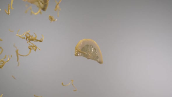 Sliced fresh lemons and lemon peels flying through in front of the camera