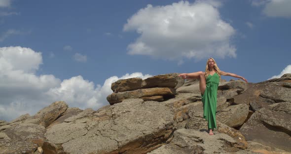 Flexible Young Woman is Lifting Her Leg Yoga on a Rocky Shore