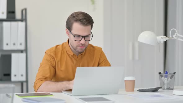 Young Man Having Loss on Laptop in Office