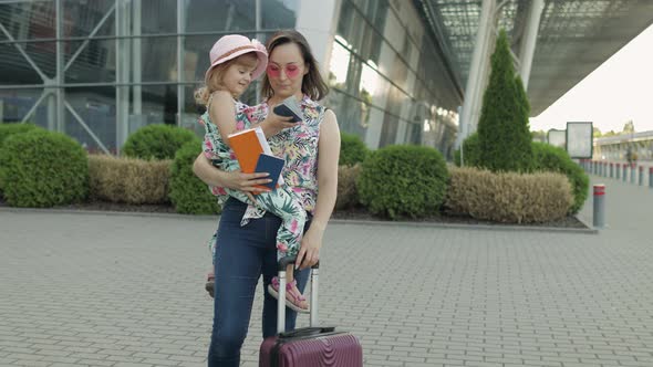 Mother and Daughter Near Airport. Woman Hold Passports and Tickets in Hand. Child and Mom Vacation