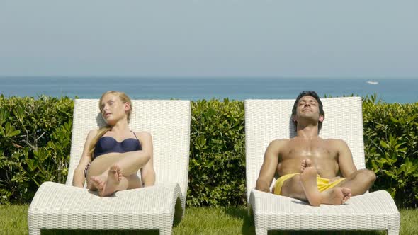 Young couple on sun loungers holding hands