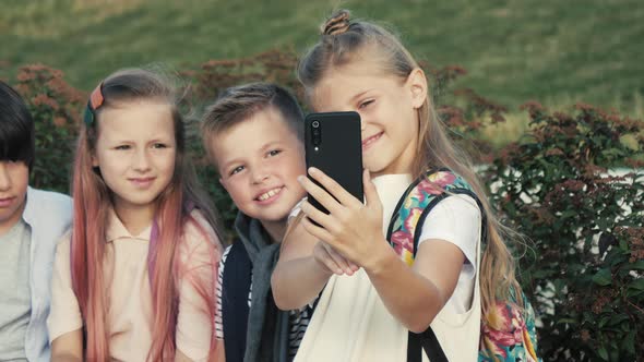 Four Children Are Sitting on a Bench and Trying To Make Selfie.