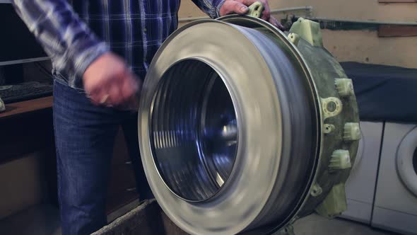 The Master Rotates the Removed Drum of the Washing Machine