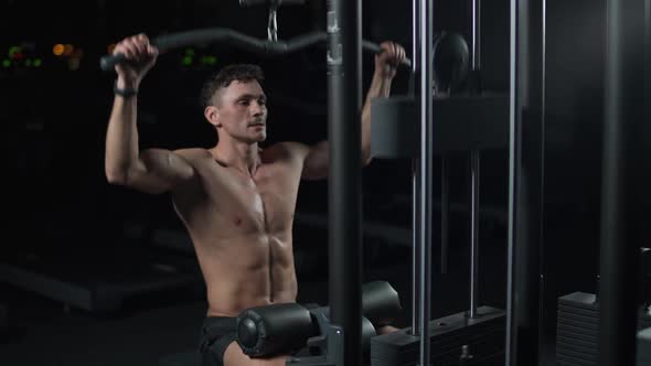 Athletic Man in the Gym Lifting Blocks on Rack Machine Training on Block Device and Gym Equipment