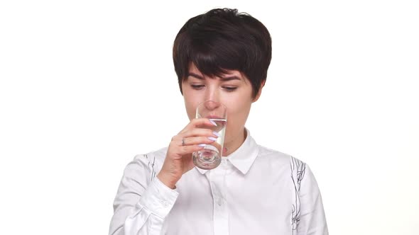 Calm Pretty Woman with Short Haircut Drinking Water From Glass Isolated Over White Background in