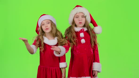 Children in Red Christmas Caps Send Air Kisses. Green Screen