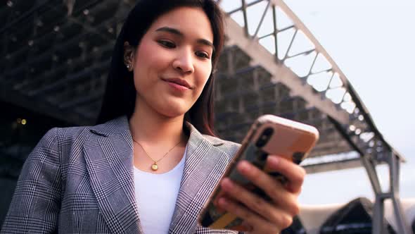 young asian woman is looking down at her mobile phone happily