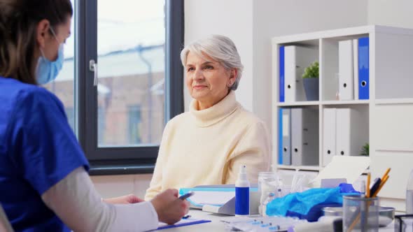 Doctor with Clipboard and Senior Woman at Hospital