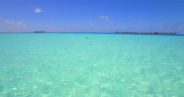 Aerial drone view of a woman floating and swimming on a tropical island