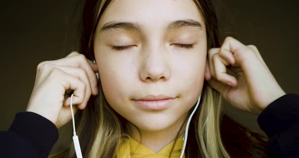 10 Years Old Girl Inserts Earphones and Nods to the Beat of the Music