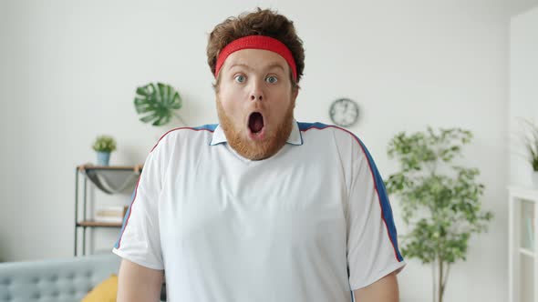 Portrait of Surprised Guy in Retro Sportswear Opening Mouth and Looking at Camera Indoors at Home