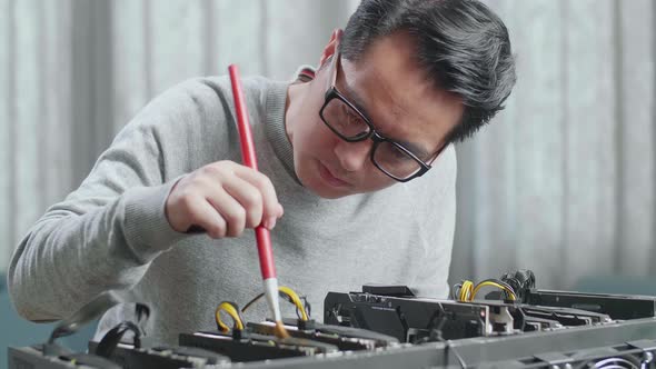 Close Up Of Asian Man Wearing Glasses Cleans The Mining Rig For Mining Cryptocurrency