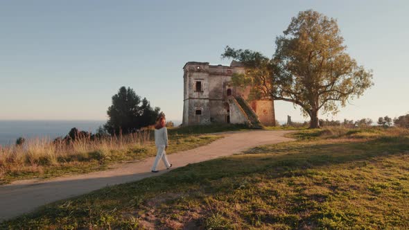 Girl dressed in white goes to a ruined castle in the countryside