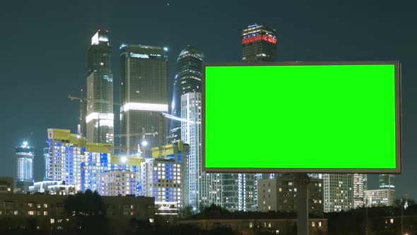 Green Screen Billboard on a Megapolis with Neon Lights, Skyscrapers on Background