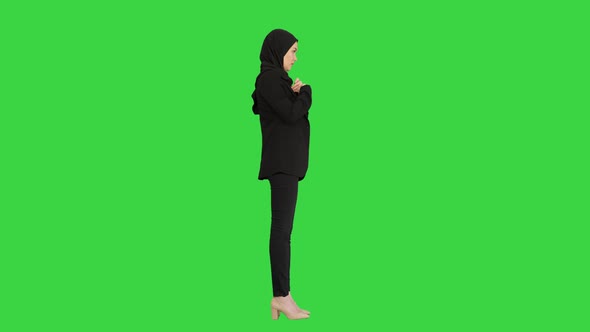 Business Woman in Hijab Standing Fixing Her Hijab on a Green Screen, Chroma Key.
