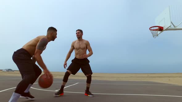 A man takes a jump shot while playing one-on-one basketball hoops on a beach court