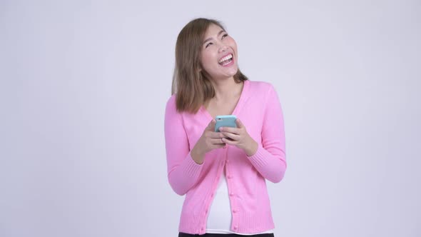 Young Happy Asian Woman Thinking While Using Phone